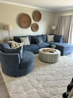 A living room features a blue sectional sofa, a round ottoman, and wall-mounted woven decor — 311 E Ocean Avenue # 309, Lantana FL 33462, LANTANA, FL