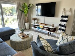 A living room features a television, media console, circular ottoman, and a large potted plant — 311 E Ocean Avenue # 309, Lantana FL 33462, LANTANA, FL