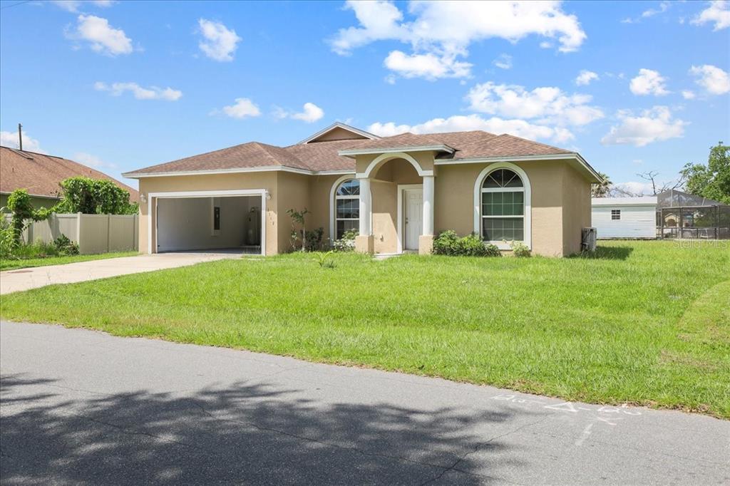 A single-story tan house with a two-car garage and an arched entryway — 1147 DONCASTER COURT, KISSIMMEE, FL