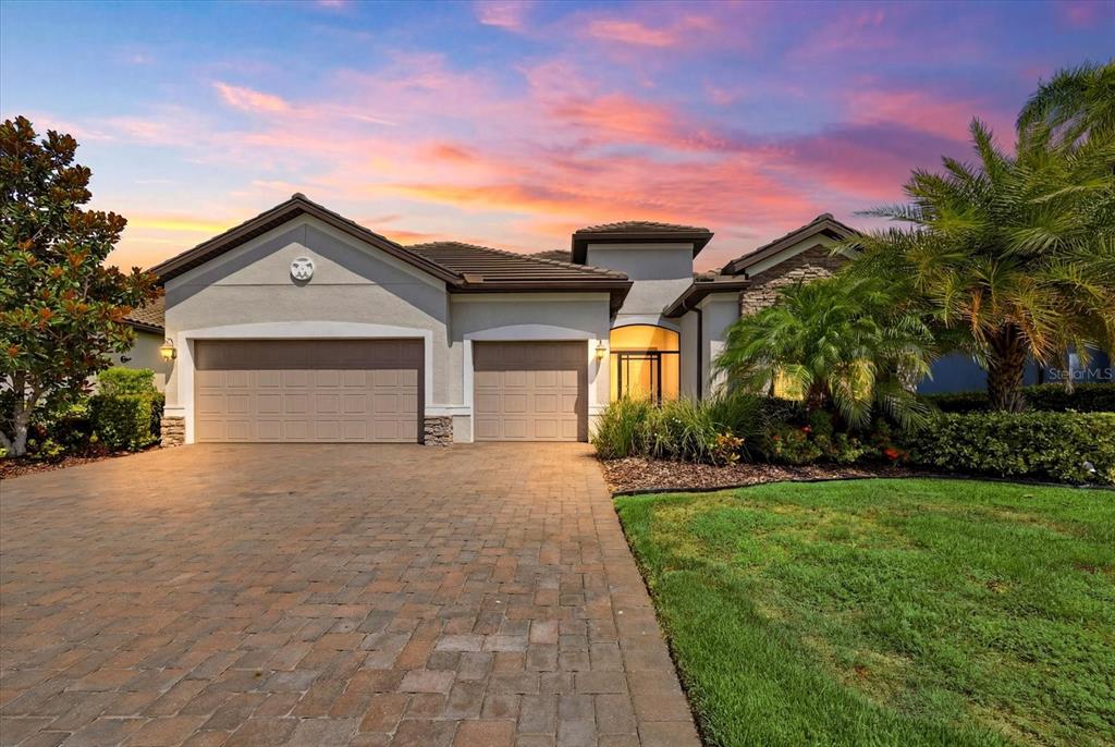 A single-story house with a paved driveway, three-car garage, and a landscaped front yard — 12021 PERENNIAL PLACE, LAKEWOOD RANCH, FL
