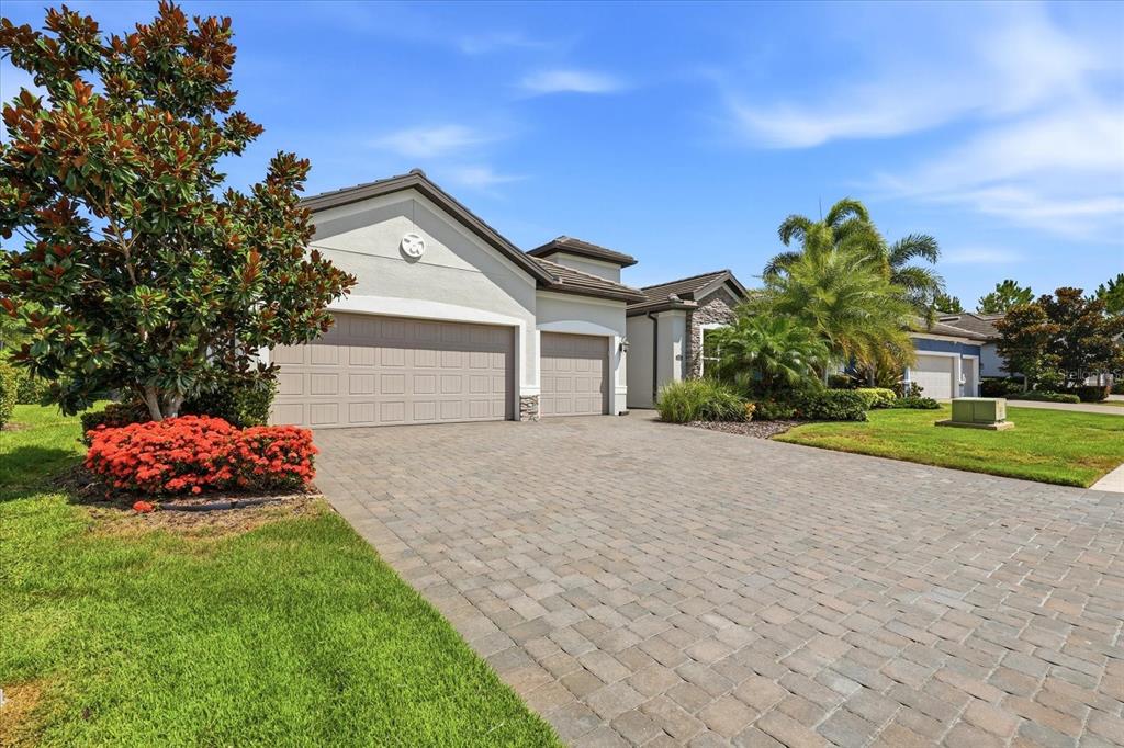 A single-story house with a paved driveway, a three-car garage, and a landscaped front yard — 12021 PERENNIAL PLACE, LAKEWOOD RANCH, FL