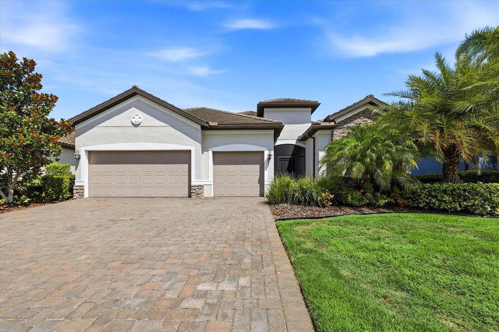 A single-story house with a paved driveway, two garage doors, and a landscaped front yard — 12021 PERENNIAL PLACE, LAKEWOOD RANCH, FL