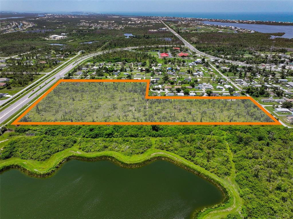 An aerial view shows a large, rectangular vacant lot outlined in orange near a pond — 8399 CYPRESS ROAD, ENGLEWOOD, FL