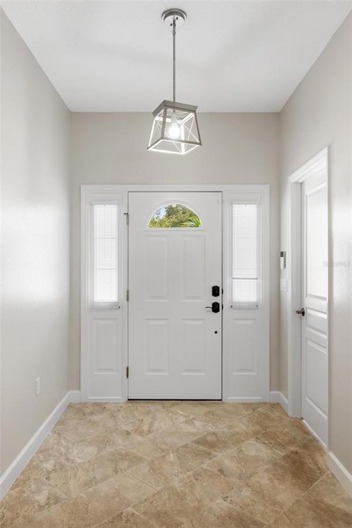 A bright entryway features a white front door with sidelights, tile flooring, and a pendant light — 4360 IOLA DRIVE, SARASOTA, FL