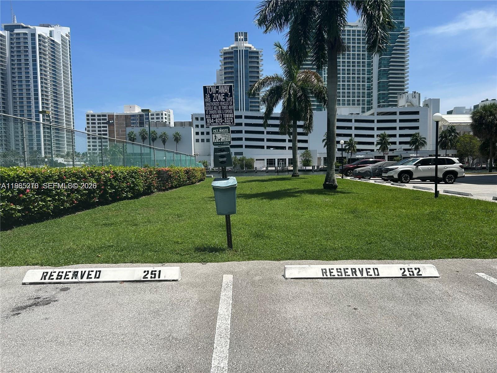 Two reserved parking spaces are situated in front of a grassy area with palm trees — 400 Leslie Dr # 308, Hallandale Beach FL 33009, HALLANDALE BEACH, FL