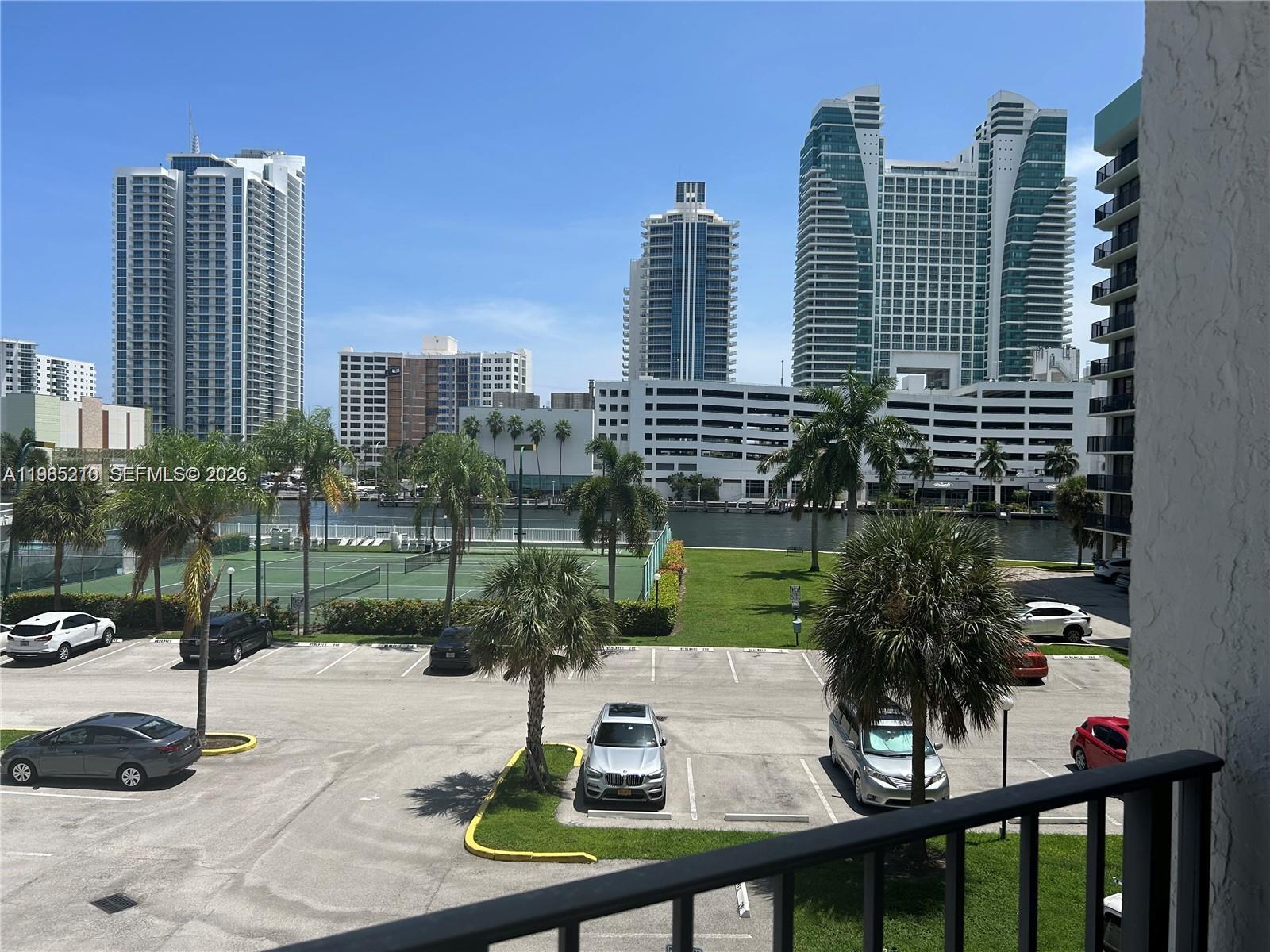An elevated view shows a parking lot, tennis courts, a waterway, and high-rise buildings — 400 Leslie Dr # 308, Hallandale Beach FL 33009, HALLANDALE BEACH, FL