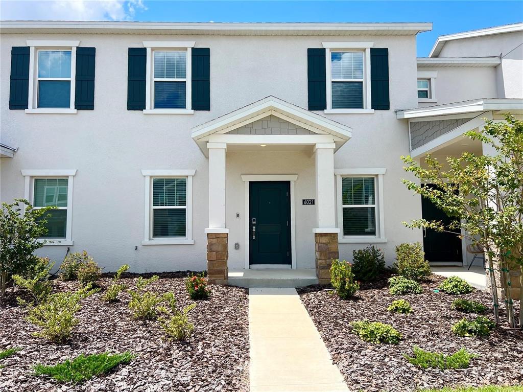 A two-story house exterior with a dark front door, stone pillars, and dark shutters — 6021 BLISSFUL STREET, CLERMONT, FL