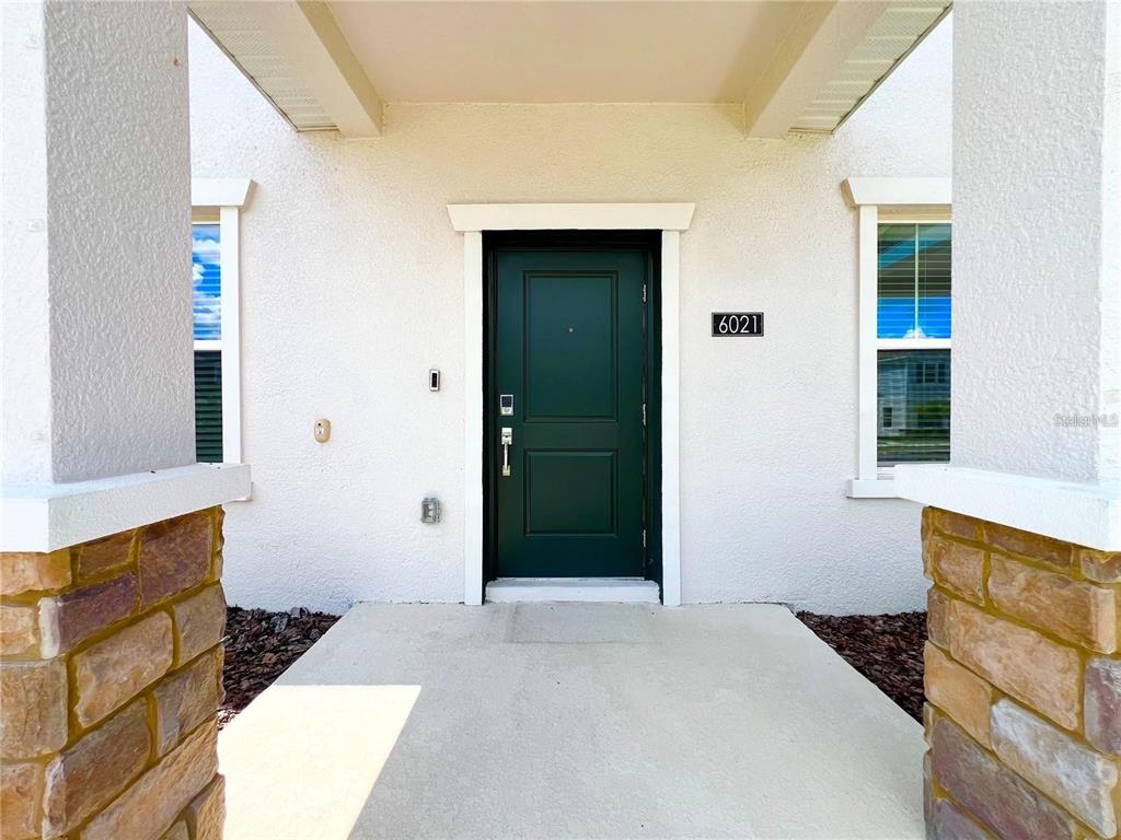 A front entryway features a dark green door, stone-based columns, and a concrete porch — 6021 BLISSFUL STREET, CLERMONT, FL