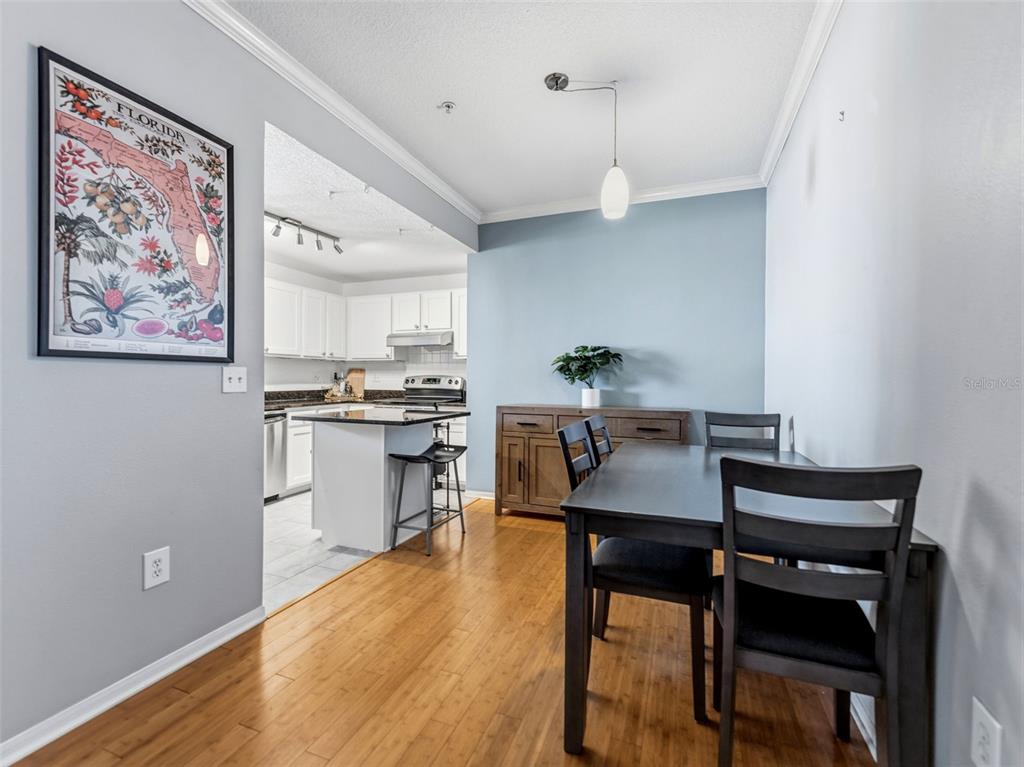 A dining area with wood floors, a dark table, and a view into the kitchen — 501 KNIGHTS RUN AVENUE UNIT 1325, TAMPA, FL