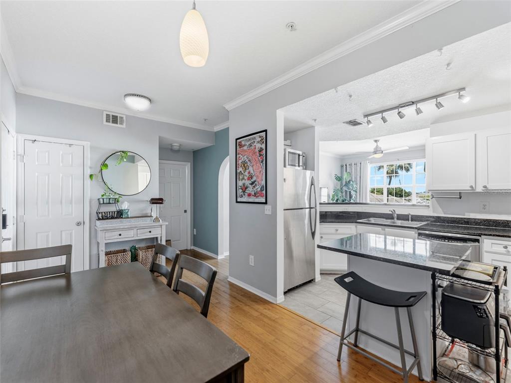 A dining area with hardwood floors leads into a kitchen featuring granite countertops and stainless appliances — 501 KNIGHTS RUN AVENUE UNIT 1325, TAMPA, FL