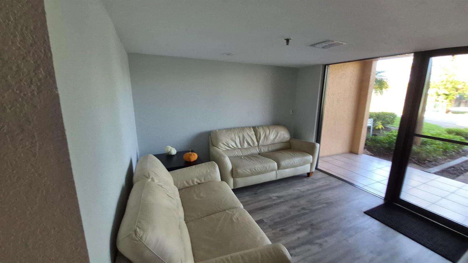 A living room features two cream-colored sofas, a small side table, and a sliding glass door — 450 Egret Circle # 9403, Delray Beach FL 33444, DELRAY BEACH, FL