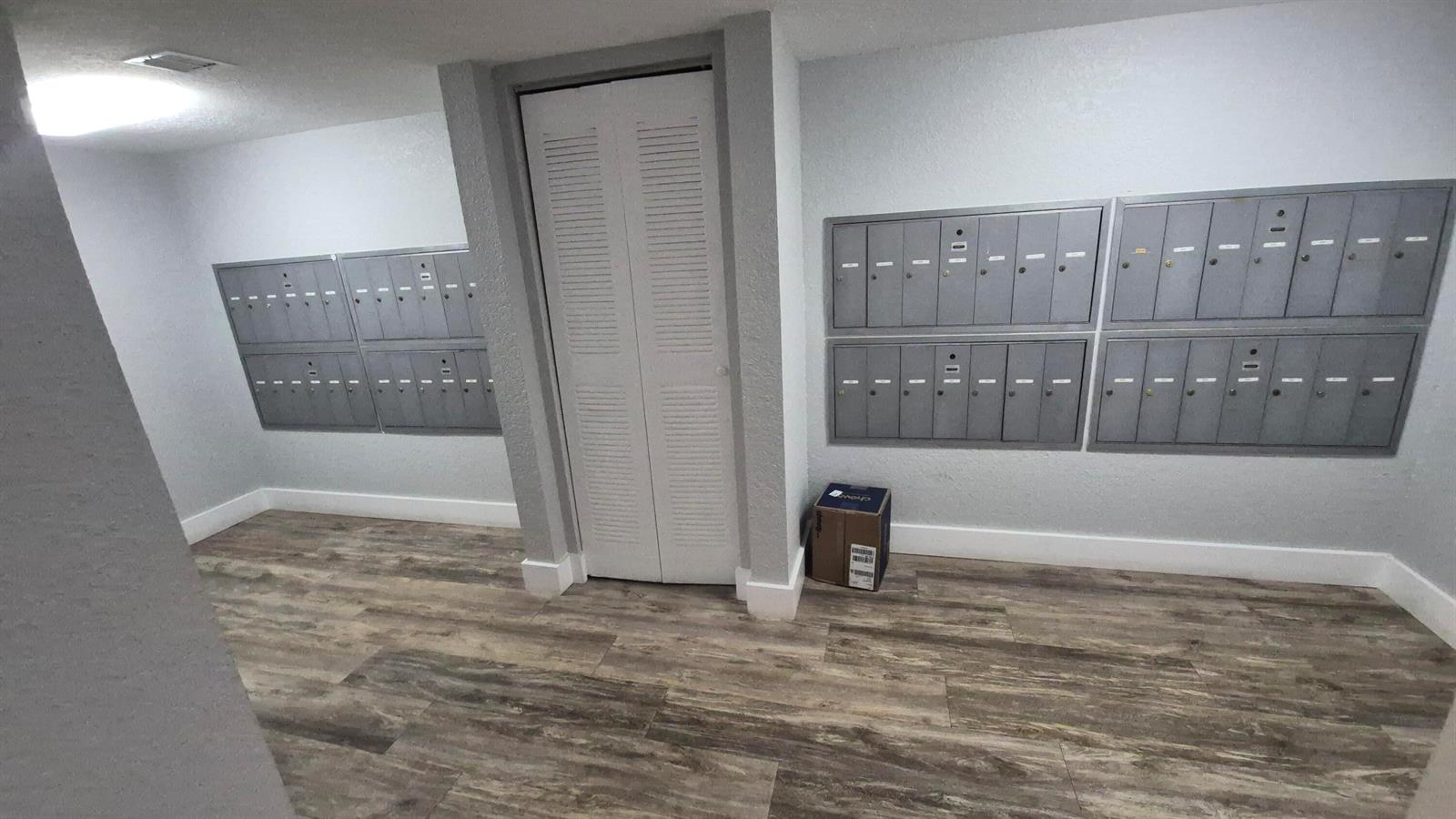 A mailroom features gray metal mailboxes on two walls, a white closet door, and flooring — 450 Egret Circle # 9403, Delray Beach FL 33444, DELRAY BEACH, FL