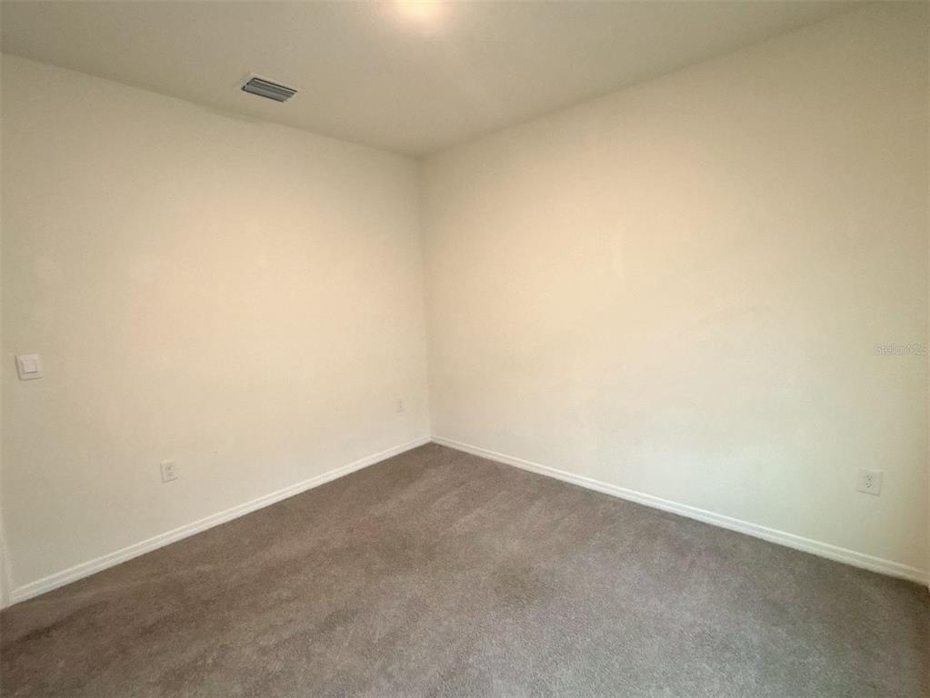 An empty bedroom features neutral walls, gray carpeting, and a ceiling vent — 500 HICKORY COURSE LOOP, OCALA, FL