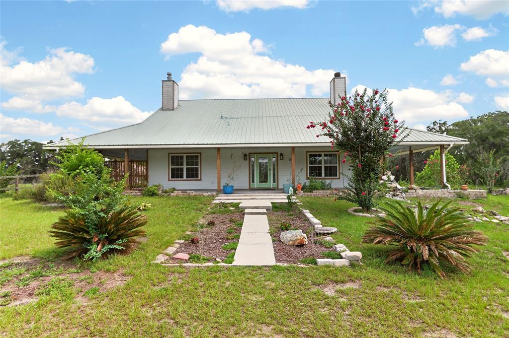 A single-story house with a metal roof and a wide front porch sits on grass — 28924 SW 30TH AVENUE, NEWBERRY, FL
