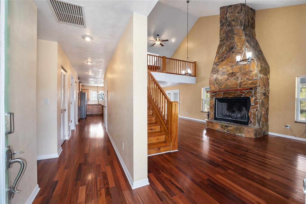 A view from an entryway into a living room with a stone fireplace and staircase — 28924 SW 30TH AVENUE, NEWBERRY, FL