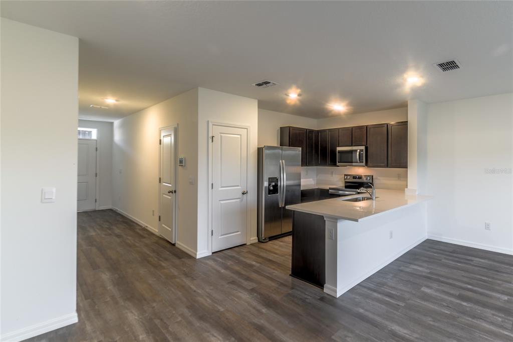 A kitchen with dark cabinets, stainless steel appliances, and a peninsula island on wood flooring — 17208 ENGLISH CHESTNUT WAY, LAND O LAKES, FL