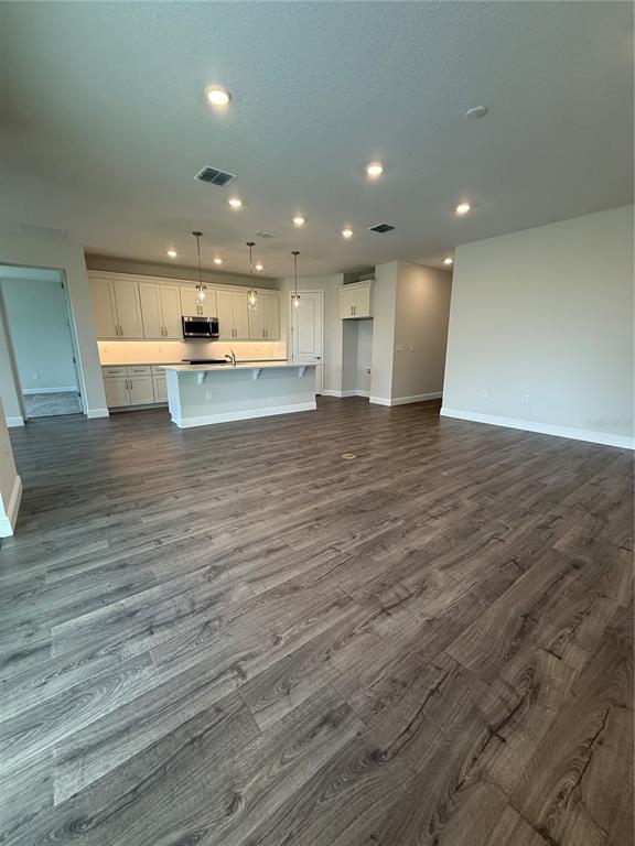 A kitchen with white cabinets, a central island, and wood-look flooring in an open space — 13769 SW 64TH STREET ROAD, OCALA, FL