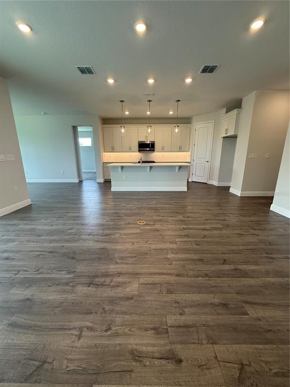A kitchen with white cabinetry and a central island sits in an open-concept room — 13769 SW 64TH STREET ROAD, OCALA, FL