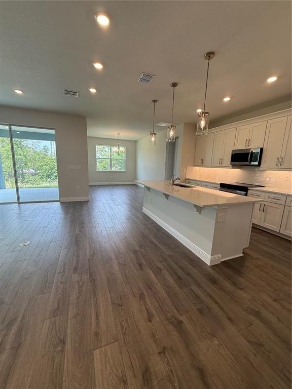 A modern kitchen with a large island and light cabinetry opens into a spacious living area — 13769 SW 64TH STREET ROAD, OCALA, FL