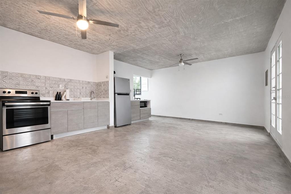 A kitchen and living area feature concrete ceilings, gray cabinetry, and light-colored tile flooring — 45 BARCELONA, GUAYAMA, PR