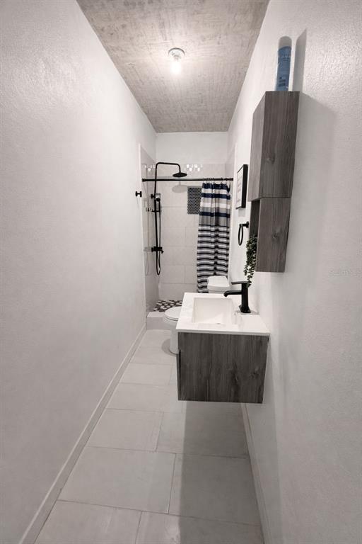 A narrow bathroom features a floating vanity, a walk-in shower with a curtain, and tile flooring — 45 BARCELONA, GUAYAMA, PR