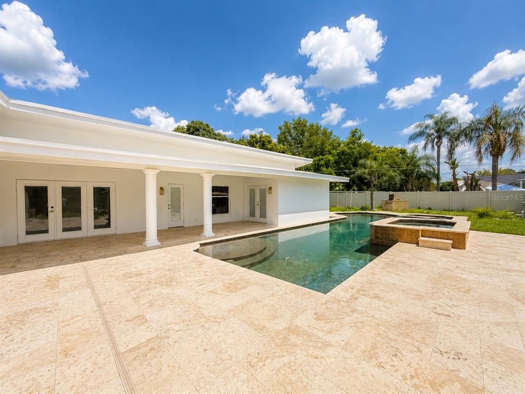 A white house exterior features a large travertine patio and an attached swimming pool — 217 YARMOUTH ROAD, CASSELBERRY, FL