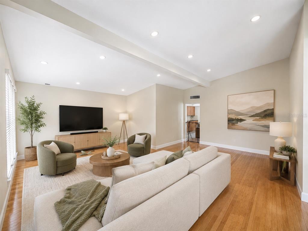 A living room features a beige sectional, two green armchairs, a television, and hardwood floors — 217 YARMOUTH ROAD, CASSELBERRY, FL