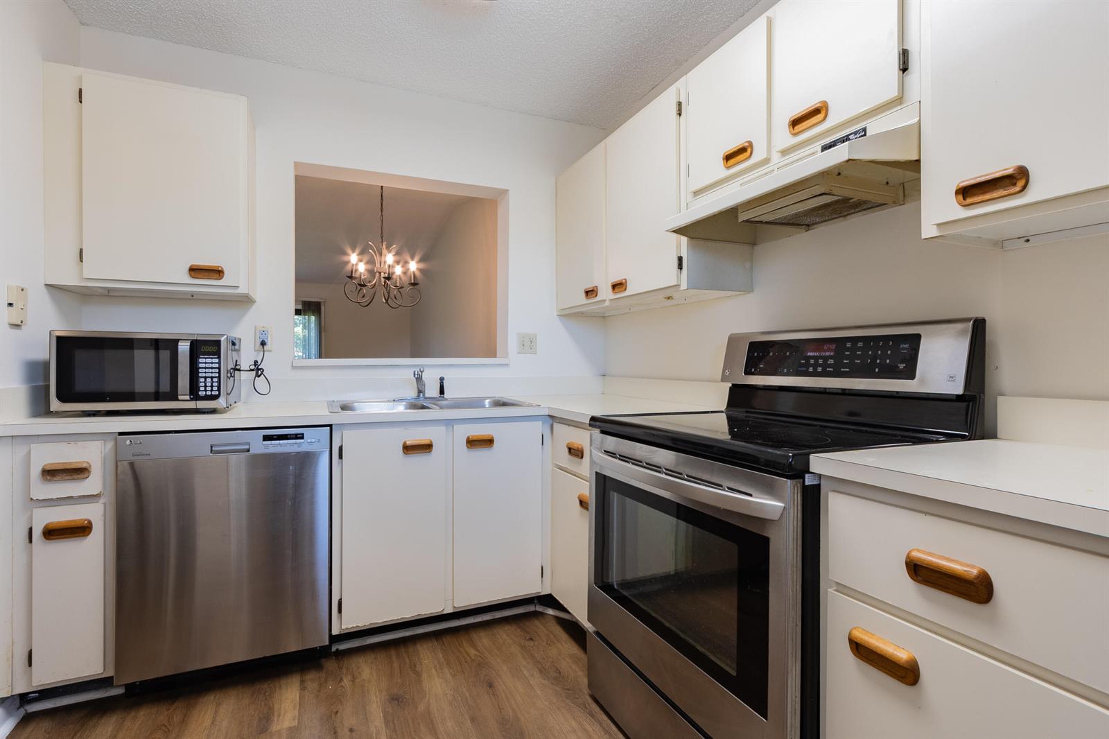A kitchen features white cabinets with wooden pulls, stainless steel appliances, and wood-look flooring — 9449 Boca Cove Circle # 911, Boca Raton FL 33428, BOCA RATON, FL