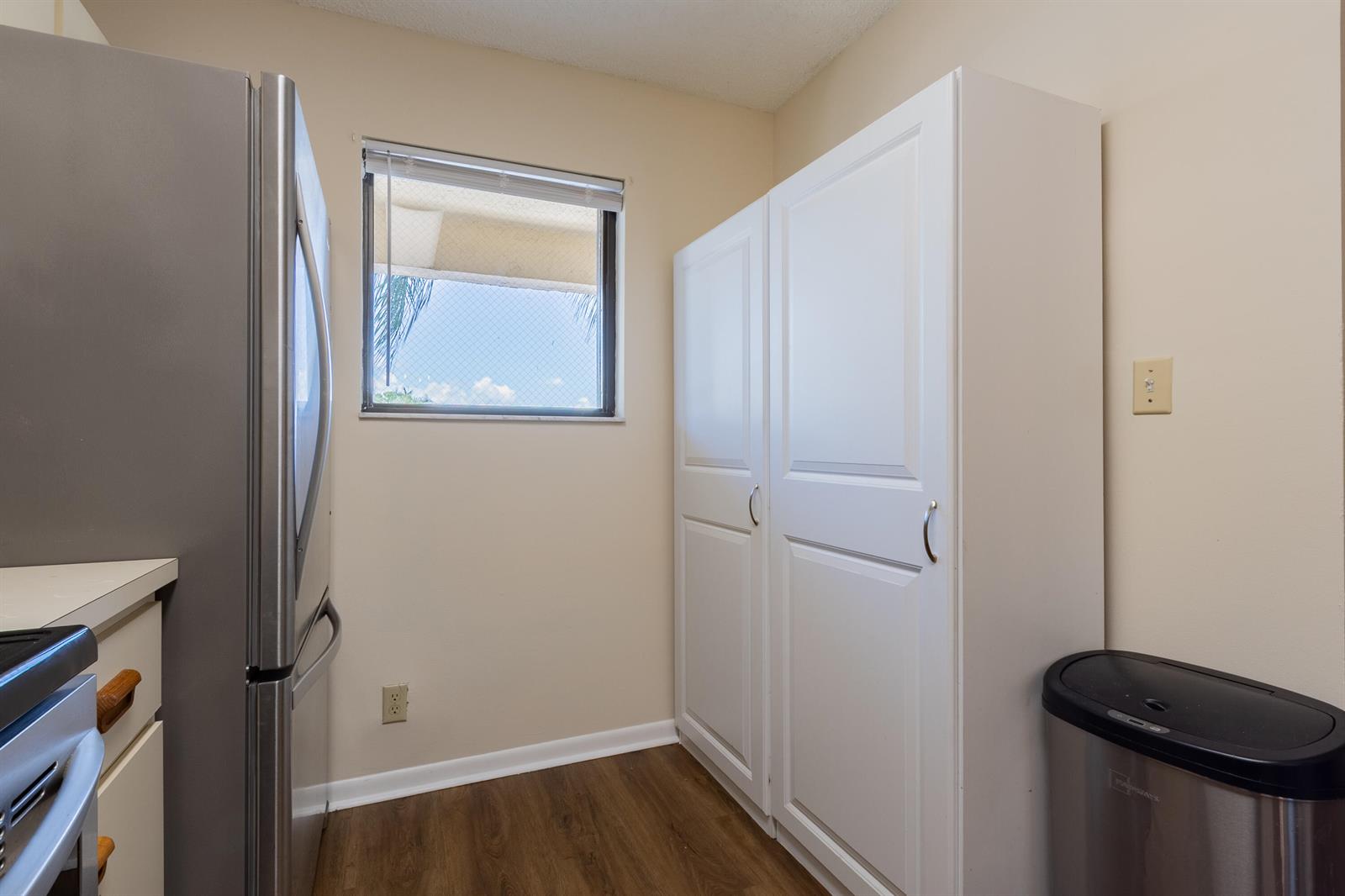 A kitchen area features a stainless steel refrigerator, white pantry cabinets, and a small window — 9449 Boca Cove Circle # 911, Boca Raton FL 33428, BOCA RATON, FL