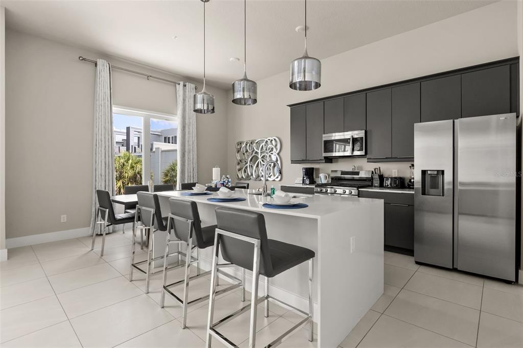 A modern kitchen features a white waterfall island, dark cabinetry, and stainless steel appliances — 7770 SANDY RIDGE DRIVE UNIT 227, REUNION, FL