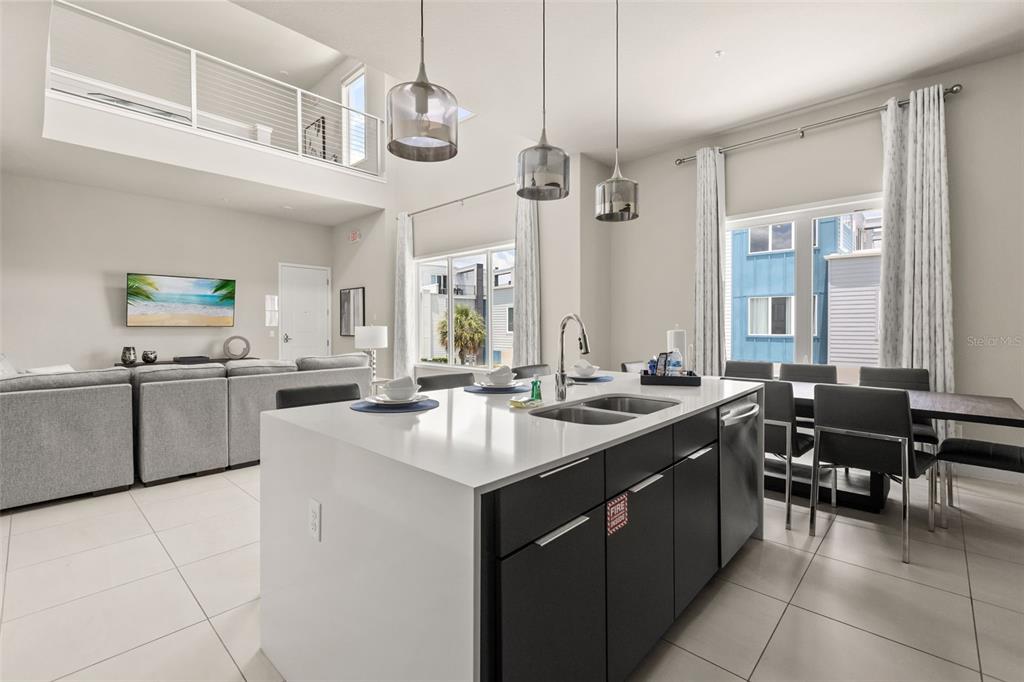 A modern kitchen with a white island and dark cabinets opens to a living area — 7770 SANDY RIDGE DRIVE UNIT 227, REUNION, FL