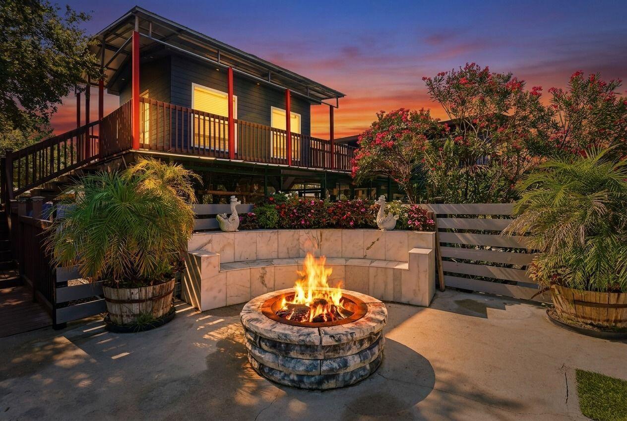 A backyard fire pit with a curved marble bench sits before a two-story elevated house — 13311 Dancy Avenue, Clewiston FL 33440, CLEWISTON, FL