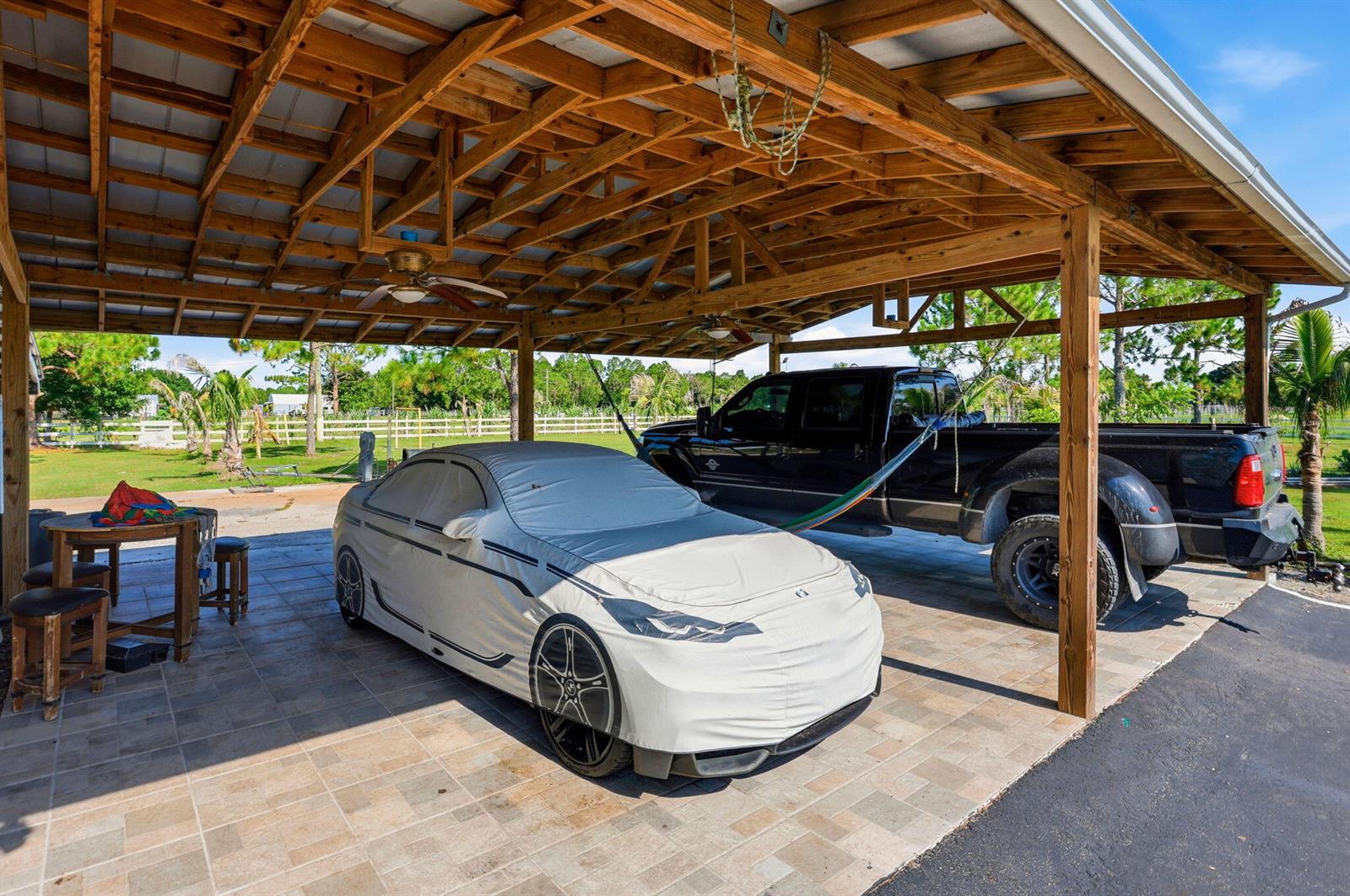 A covered outdoor patio features a tiled floor, a car under a cover, and a truck — 13311 Dancy Avenue, Clewiston FL 33440, CLEWISTON, FL