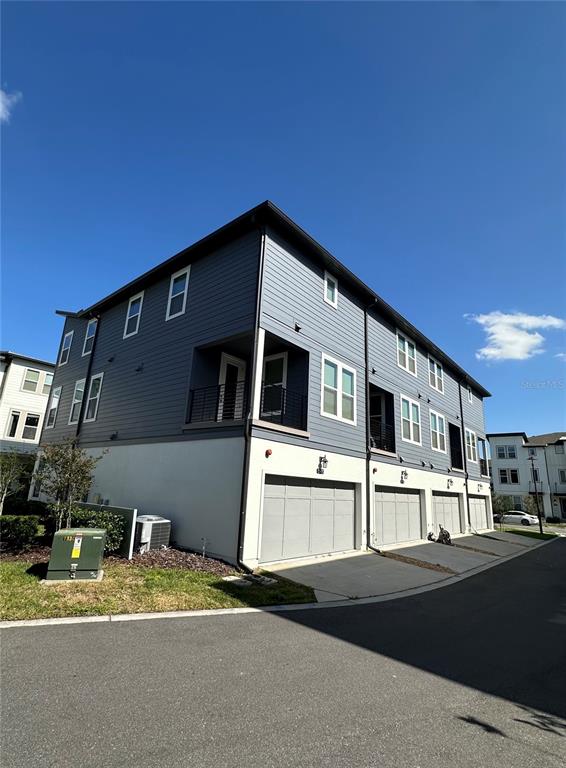 A three-story townhouse with blue siding, white stucco lower level, and three garage doors — 12673 YOSHINO ALLEY, ORLANDO, FL
