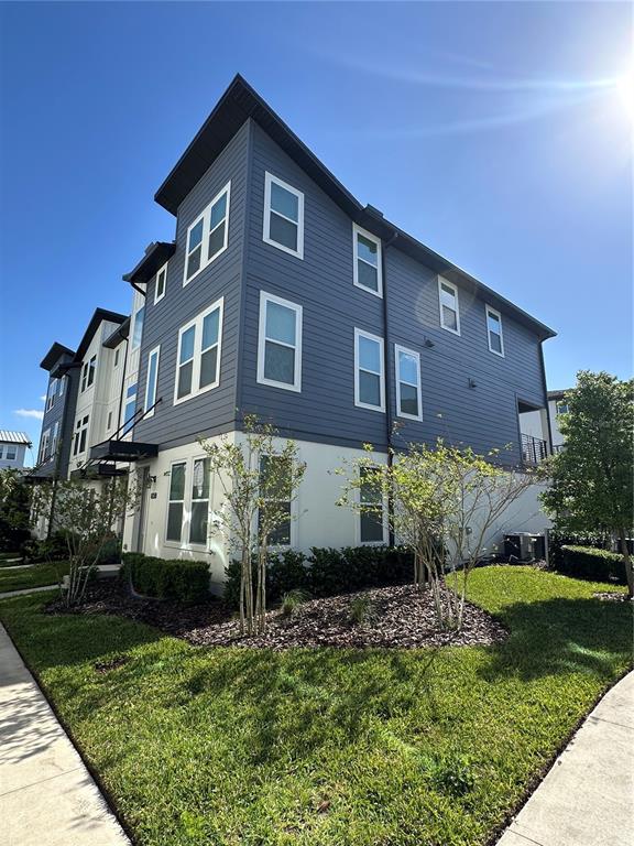 A three-story townhouse with blue horizontal siding and a white stucco ground floor exterior — 12673 YOSHINO ALLEY, ORLANDO, FL