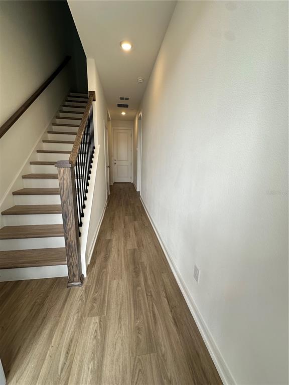 A hallway features light wood-look flooring, a staircase with dark wood railings, and white walls — 12673 YOSHINO ALLEY, ORLANDO, FL