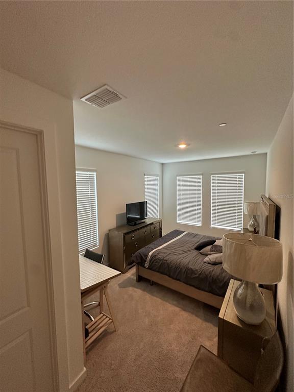 A bedroom features a bed, a dresser with a television, and a small desk — 12673 YOSHINO ALLEY, ORLANDO, FL