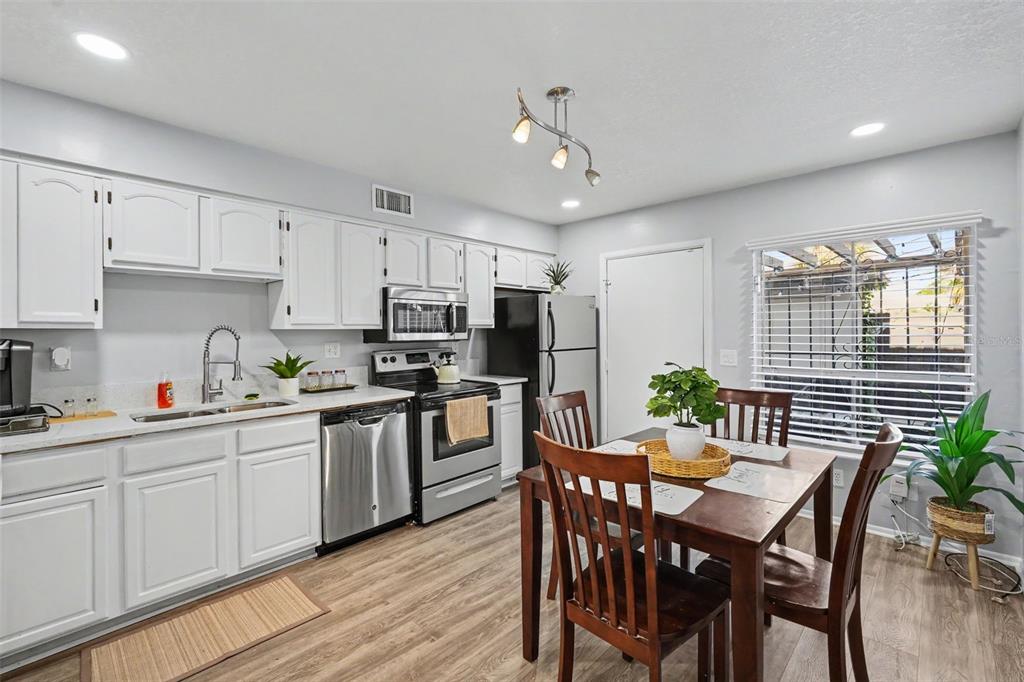 A kitchen with white cabinets, stainless steel appliances, and a wooden dining table and chairs — 4505 LA CAPRI COURT, TAMPA, FL