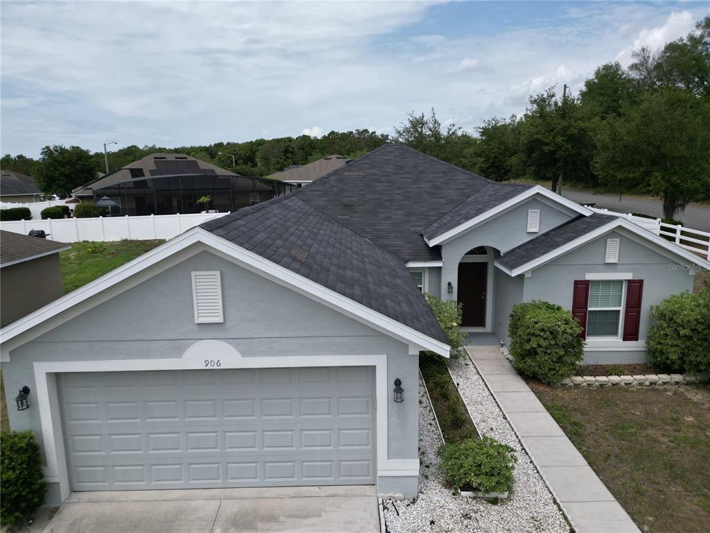 An aerial view of a single-story gray house with a dark shingled roof and garage — 906 CHESTNUT DRIVE, FRUITLAND PARK, FL
