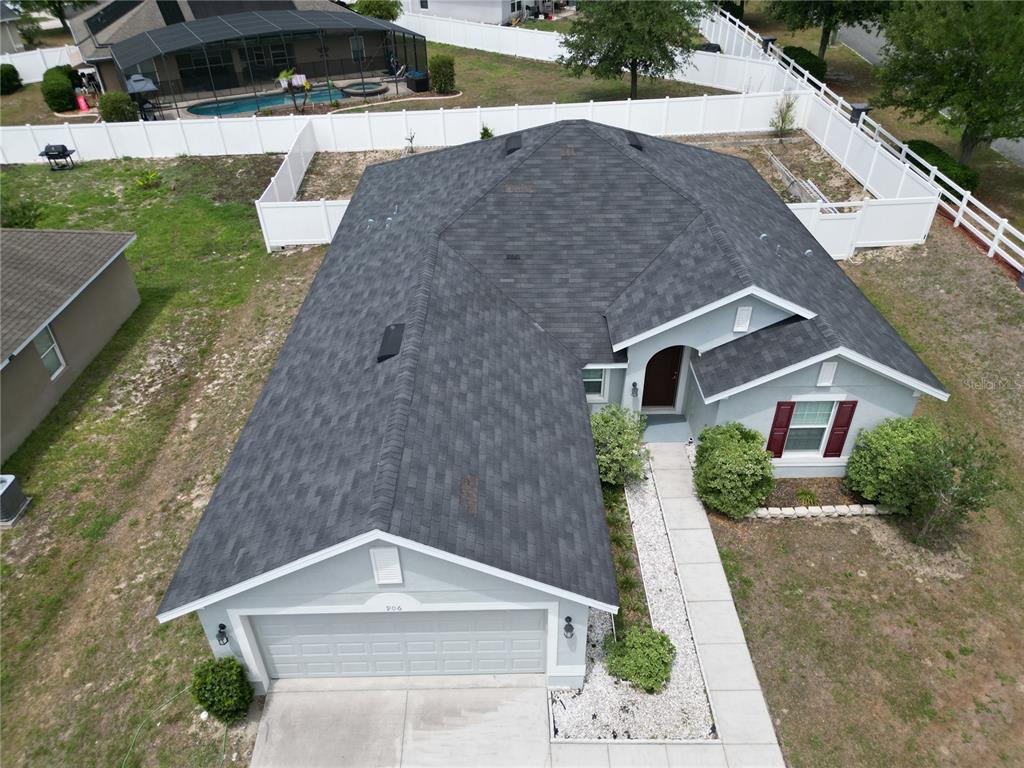 An aerial view of a single-story house with a gray shingle roof and garage — 906 CHESTNUT DRIVE, FRUITLAND PARK, FL
