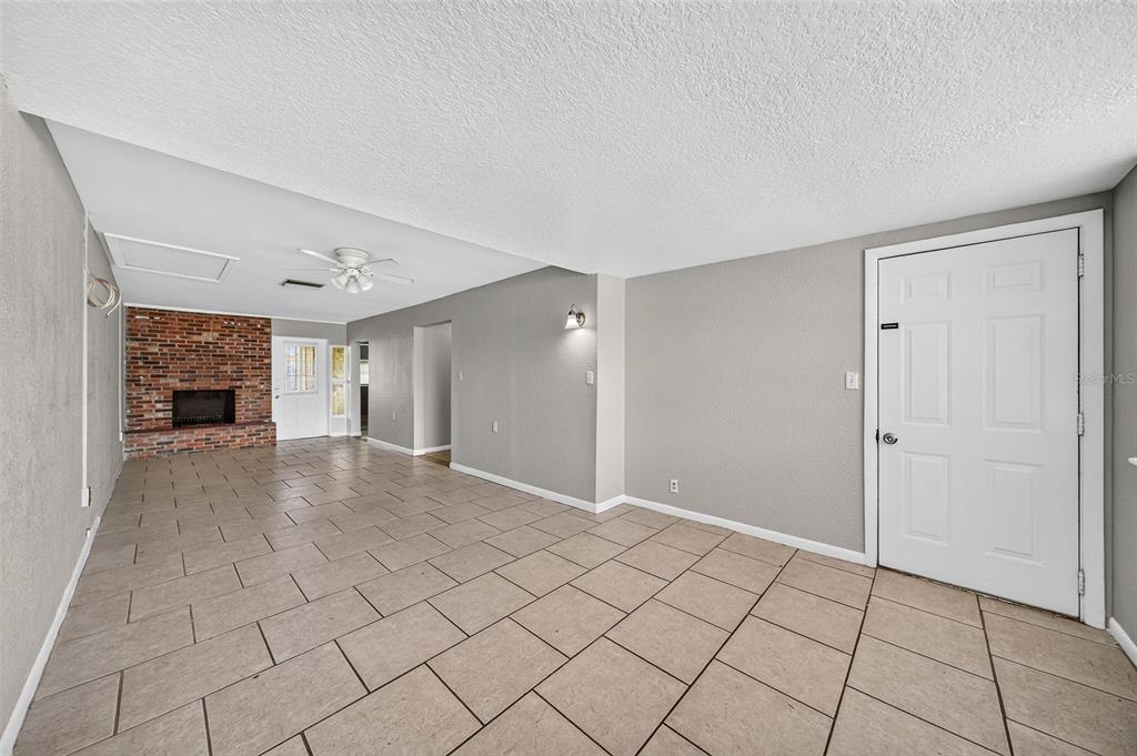 A living room with light tile flooring, gray walls, and a brick fireplace — 708 N SAINT CLAIR ABRAMS AVENUE, TAVARES, FL