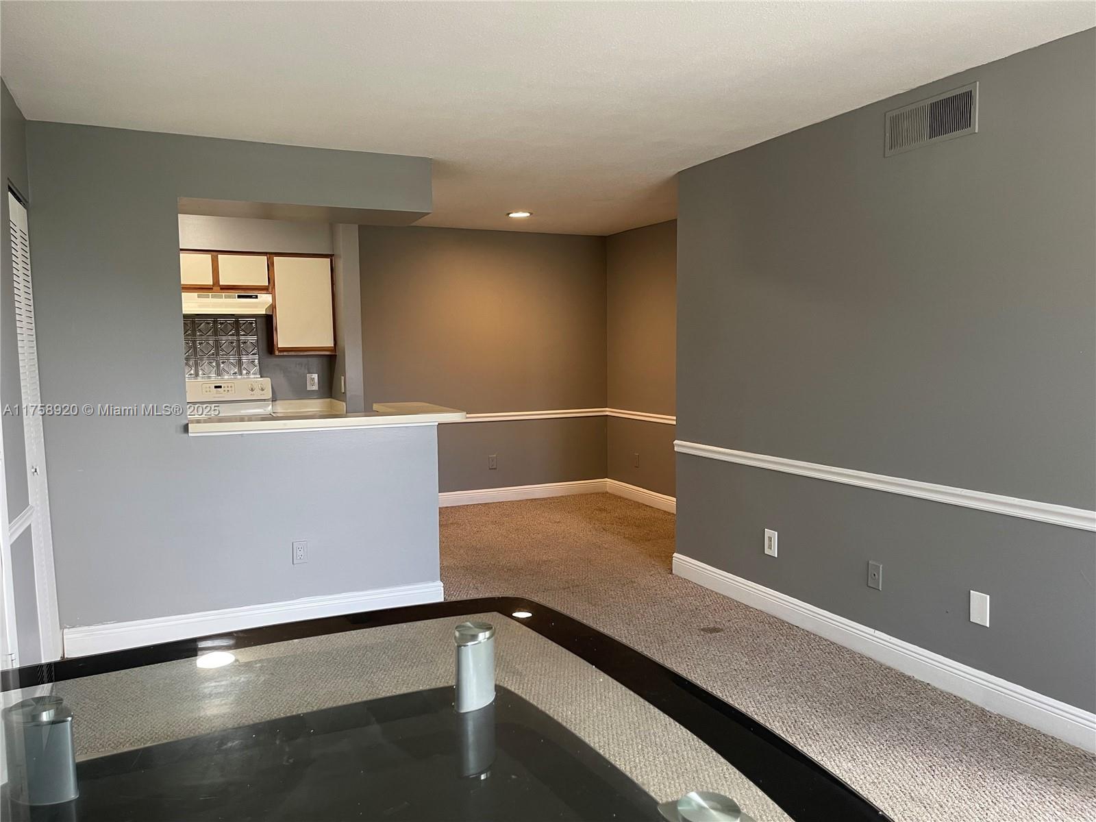 A living area with gray walls, white trim, and a pass-through window to the kitchen — 1247 SW 46th Ave # 1312, Pompano Beach FL 33069, POMPANO BEACH, FL