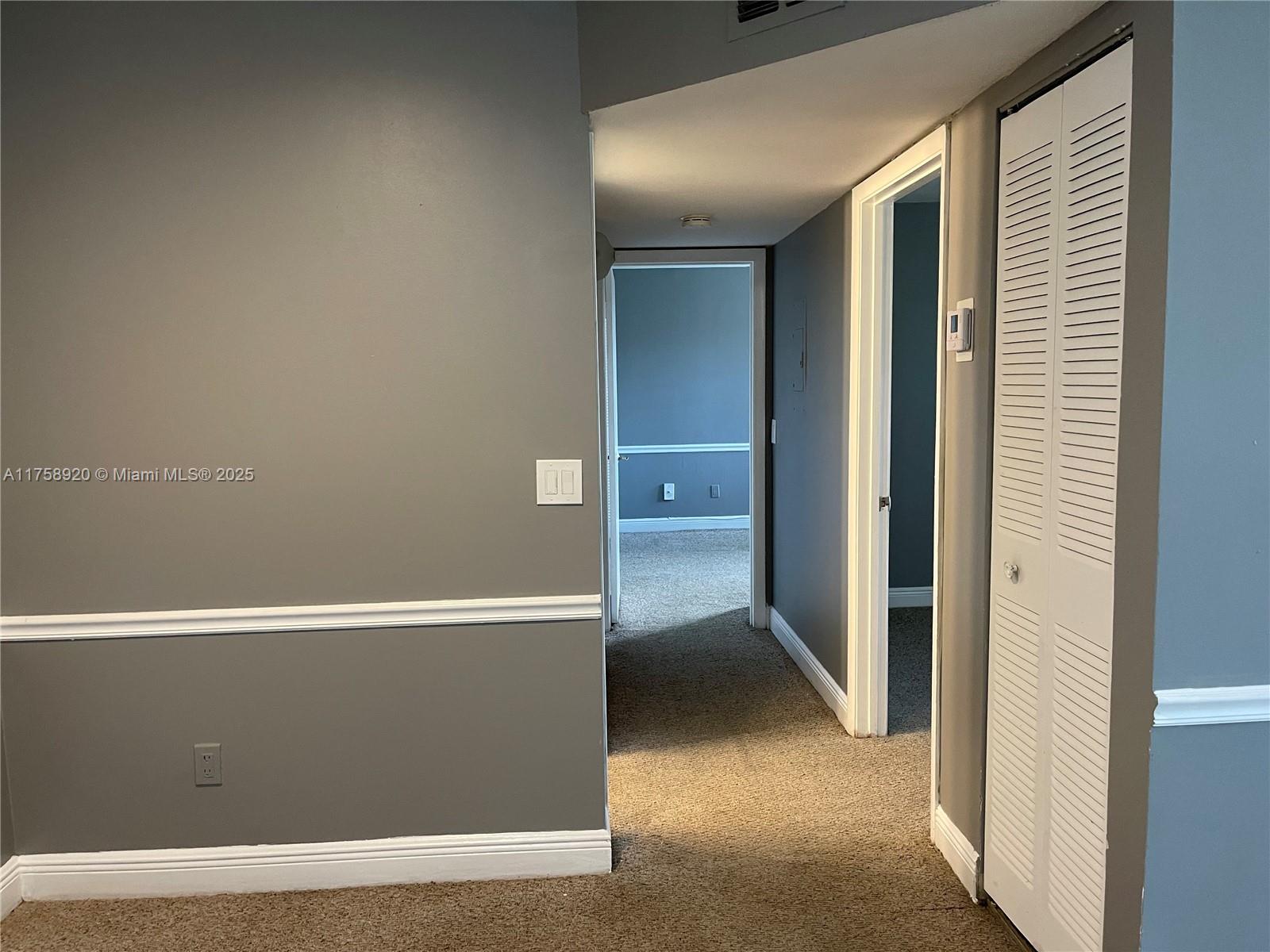 A hallway with gray walls, white trim, and carpeted floors leads to an adjacent room — 1247 SW 46th Ave # 1312, Pompano Beach FL 33069, POMPANO BEACH, FL