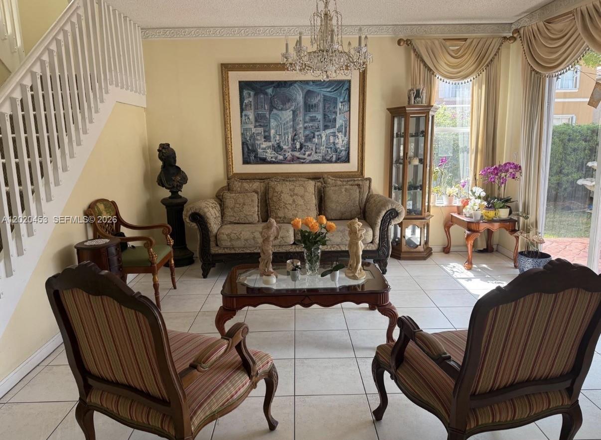 A formal living room features tiled floors, a chandelier, a sofa, and two striped armchairs — 15619 SW 112th Dr, Miami FL 33196, MIAMI, FL