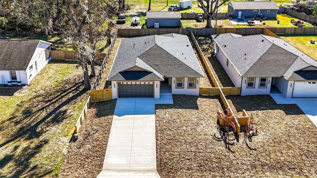 An aerial view shows a new suburban house with a concrete driveway and fenced yard — 288 ROOSEVELT AVENUE, MASARYKTOWN, FL