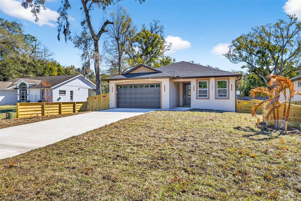 A single-story house with a gray garage, beige exterior, and a concrete driveway — 288 ROOSEVELT AVENUE, MASARYKTOWN, FL