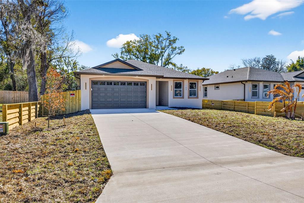 A single-story house with a two-car garage and a concrete driveway under a blue sky — 288 ROOSEVELT AVENUE, MASARYKTOWN, FL