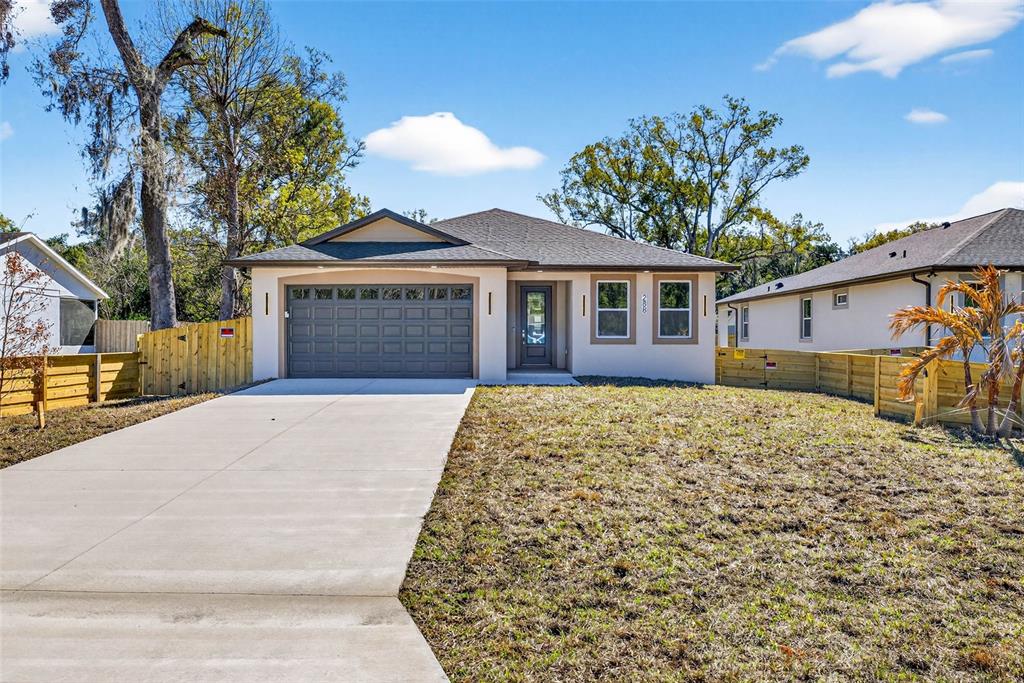 A single-story house with a gray garage door, beige siding, and a concrete driveway — 288 ROOSEVELT AVENUE, MASARYKTOWN, FL