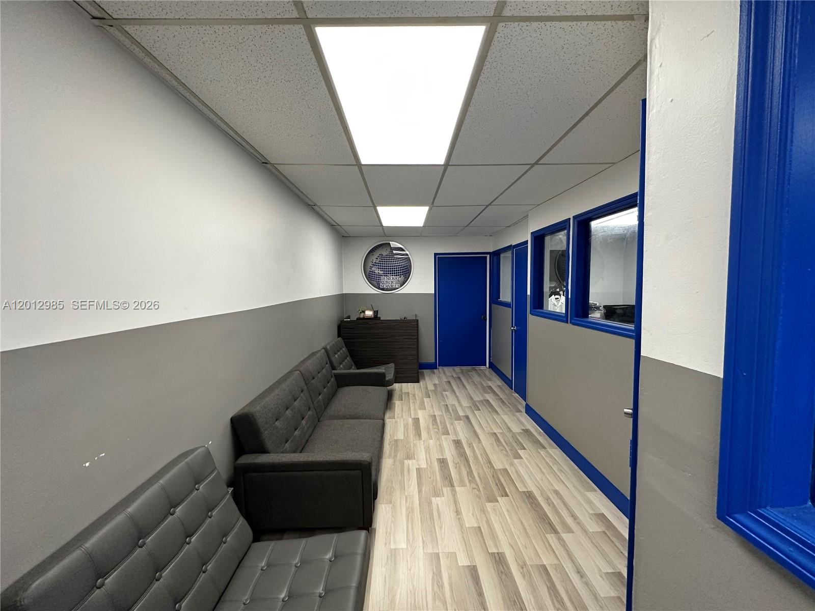 A waiting area features grey walls, wood-look flooring, blue door frames, and grey seating — 510 NE 167th St # 510, Miami FL 33162, MIAMI, FL
