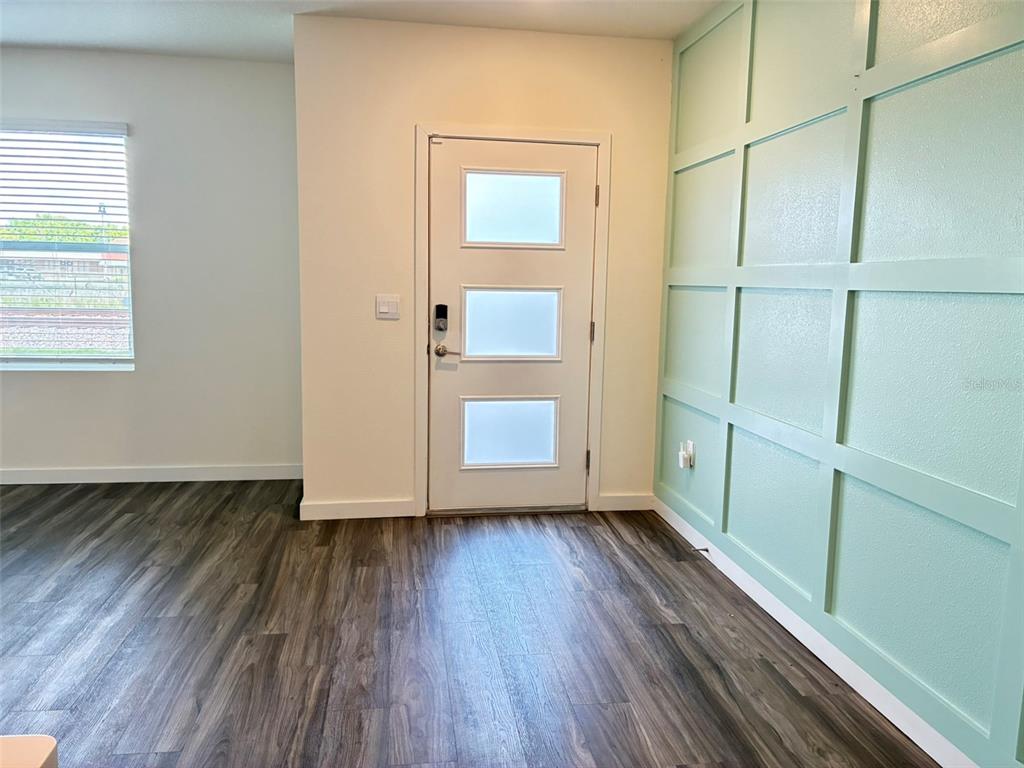 An entryway features wood-look flooring, a white door with three glass panels, and a mint-colored accent wall — 553 JOHN L MICA WAY, LONGWOOD, FL